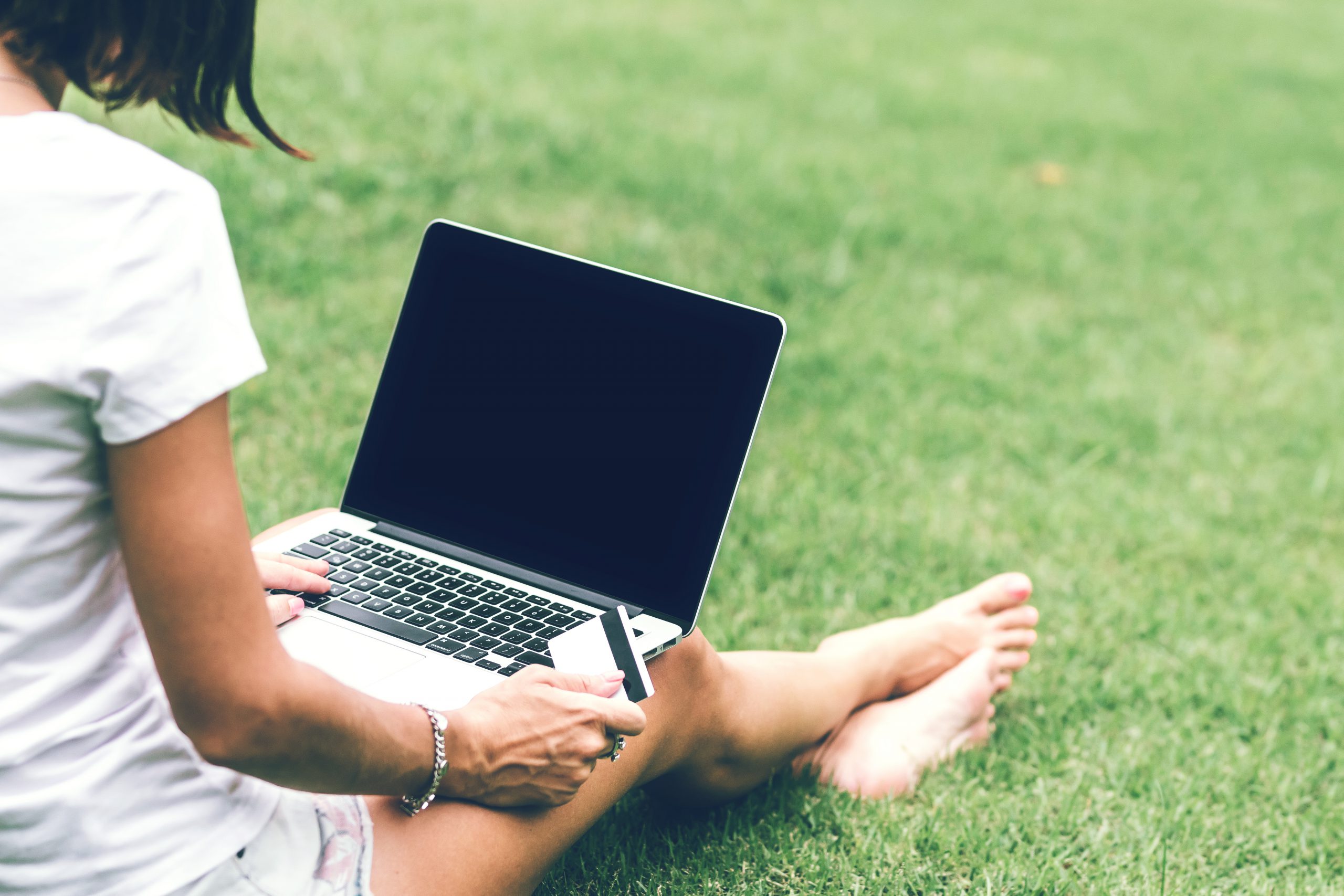 Woman online shopping concept. Woman in the green park with modern laptop. Bali island. Indonesia.