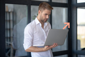 ragazzo con camicia bianca che lavora al computer vicino ad una vetrata grande